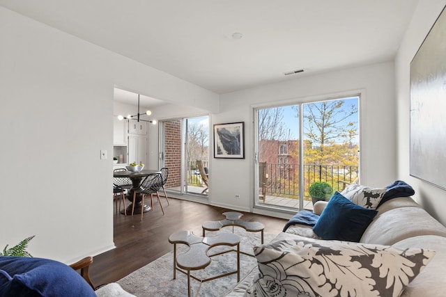 living room featuring a chandelier, wood finished floors, visible vents, and baseboards