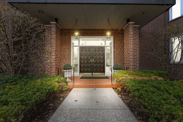 doorway to property featuring covered porch and brick siding