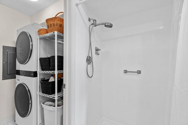 bathroom with a tile shower and stacked washer and dryer