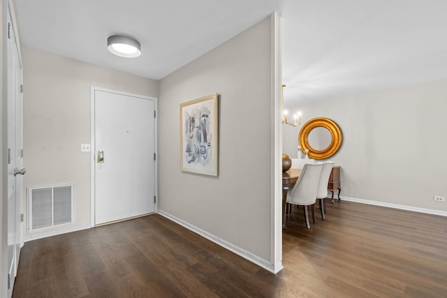 foyer featuring baseboards, visible vents, a chandelier, and dark wood-type flooring