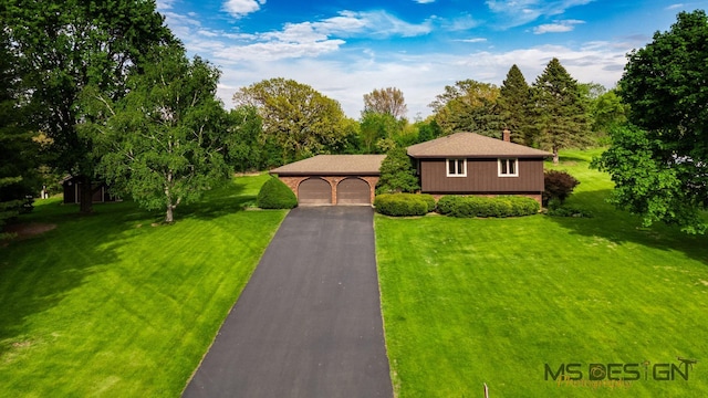 view of front of home with a front yard, driveway, and a detached garage