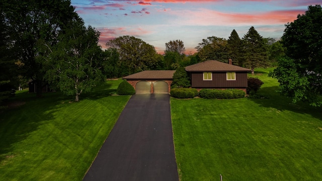 view of front of property with asphalt driveway and a lawn