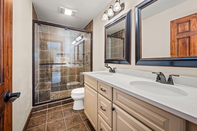 bathroom featuring a shower stall, toilet, double vanity, and tile patterned floors