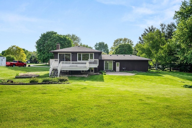 back of property with a deck, a lawn, a chimney, and a patio area