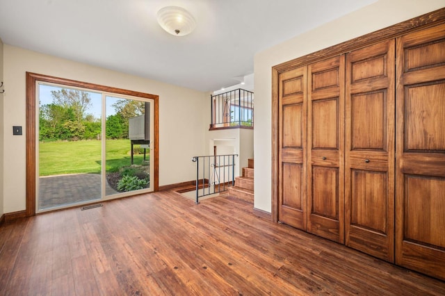 doorway with dark wood-style floors, baseboards, and stairway