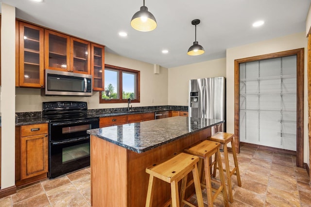 kitchen with stainless steel appliances, a breakfast bar, a sink, decorative light fixtures, and glass insert cabinets