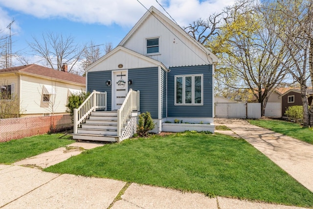 bungalow-style house featuring fence, concrete driveway, and a front lawn