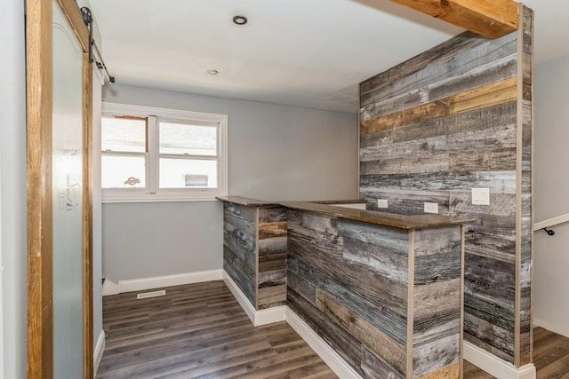 bar with a dry bar, wooden walls, wood finished floors, and baseboards