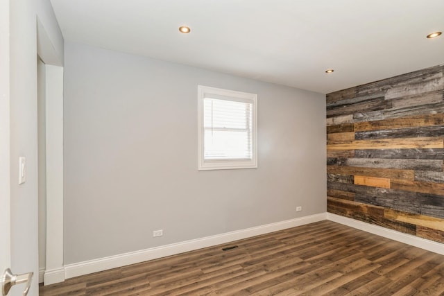 empty room featuring wood walls, dark wood-style flooring, recessed lighting, and baseboards