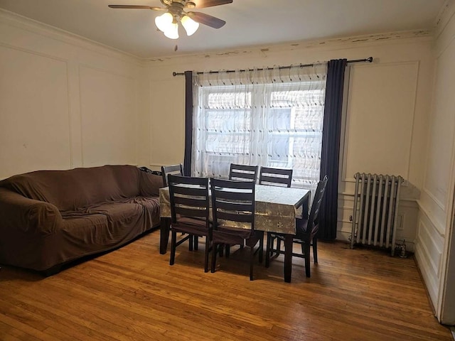 dining room featuring ornamental molding, radiator, a ceiling fan, and wood finished floors
