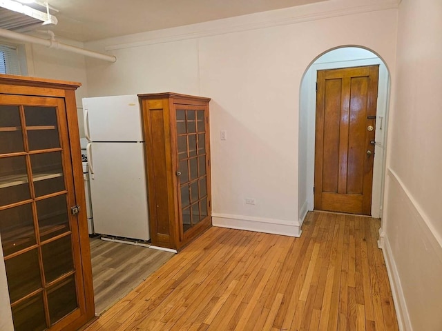 entryway with light wood-style flooring, baseboards, and arched walkways