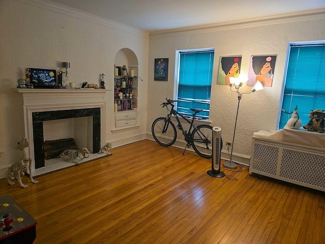 interior space with a premium fireplace, baseboards, crown molding, arched walkways, and hardwood / wood-style floors