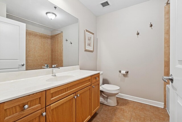 bathroom with toilet, baseboards, vanity, tile patterned flooring, and a shower