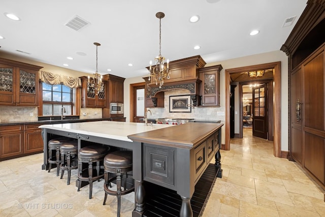 546 Oak Knoll Rd, Barrington Hills, IL 60010 - kitchen featuring stainless steel microwave, a chandelier, a large island, glass insert cabinets, and backsplash