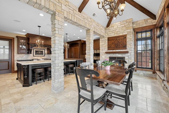 546 Oak Knoll Rd, Barrington Hills, IL 60010 - dining space featuring beam ceiling, decorative columns, stone tile flooring, and a fireplace
