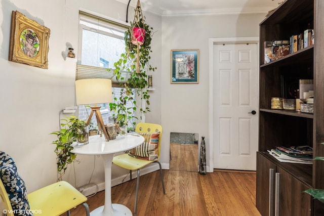 interior space featuring baseboards, wood finished floors, and crown molding