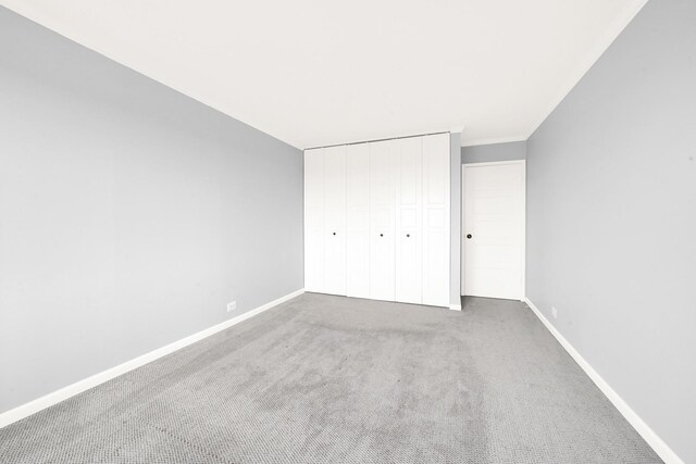 unfurnished bedroom featuring carpet floors, a closet, and baseboards