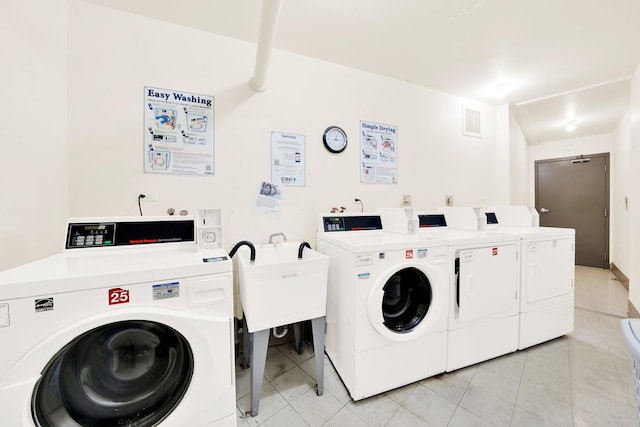 common laundry area featuring visible vents, washer and clothes dryer, a sink, and light tile patterned flooring