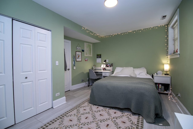 bedroom with baseboards, wood finished floors, visible vents, and a closet