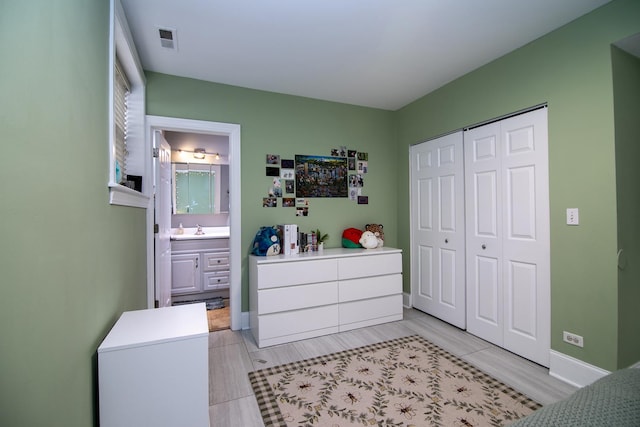 bedroom with visible vents, connected bathroom, a sink, a closet, and baseboards