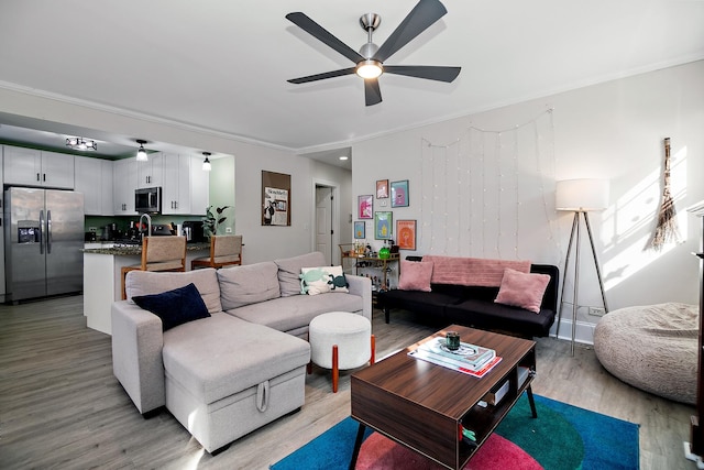 living room with light wood-type flooring, crown molding, and ceiling fan