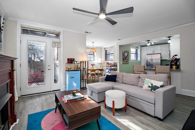 living area featuring ceiling fan, crown molding, wood finished floors, and visible vents