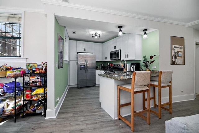 kitchen with light wood finished floors, stainless steel appliances, a peninsula, and baseboards