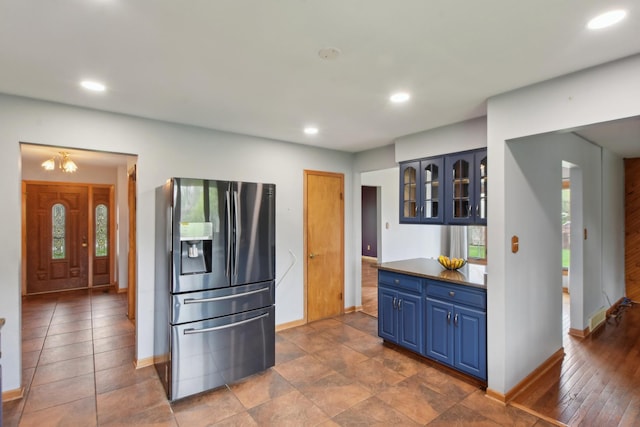 kitchen featuring blue cabinets, recessed lighting, glass insert cabinets, stainless steel fridge with ice dispenser, and baseboards