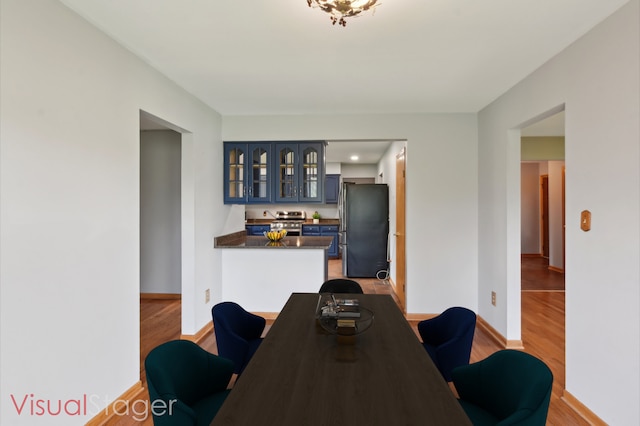 dining area with wood finished floors, bar area, and baseboards