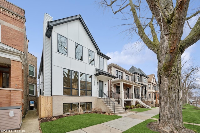 view of front facade featuring a chimney, a front yard, stucco siding, brick siding, and a residential view
