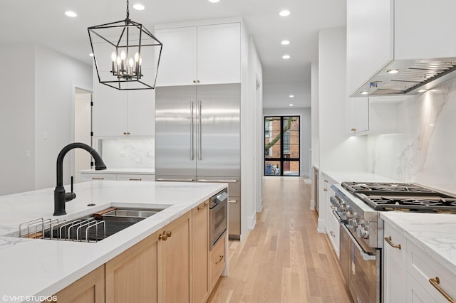 kitchen with a sink, light wood-style flooring, decorative light fixtures, high end stainless steel range oven, and recessed lighting