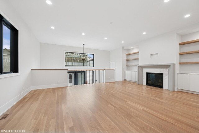 unfurnished living room with light wood-style flooring, baseboards, visible vents, recessed lighting, and a chandelier