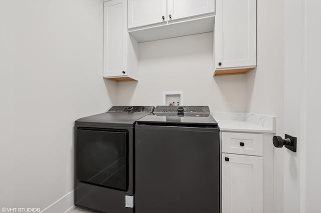 clothes washing area featuring washing machine and dryer, baseboards, and cabinet space