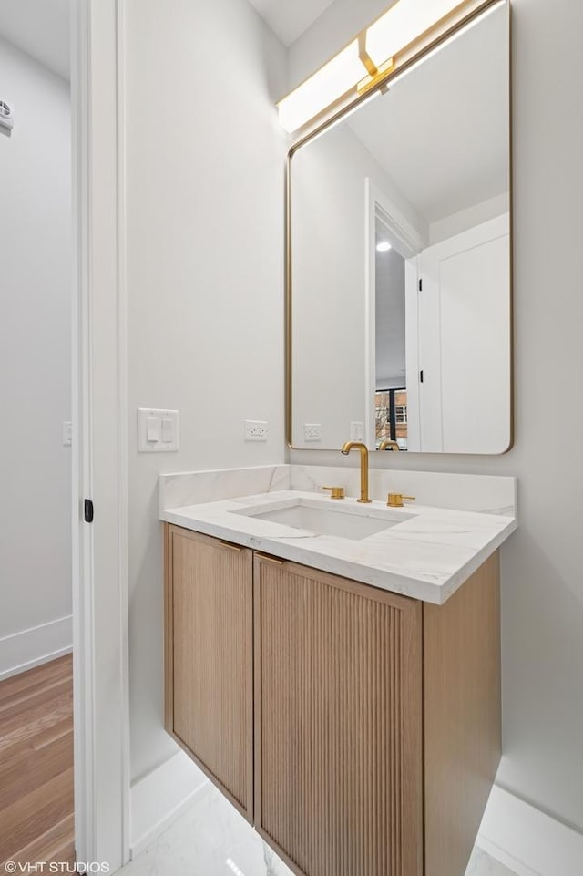 bathroom with baseboards, wood finished floors, and vanity