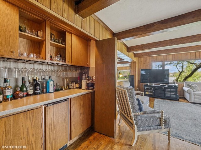 bar featuring a sink, beamed ceiling, wood finished floors, and indoor bar