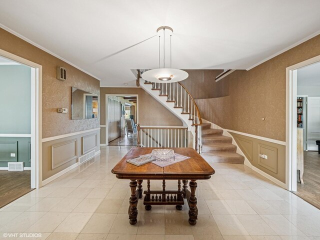 foyer entrance featuring stairs, visible vents, ornamental molding, and a decorative wall