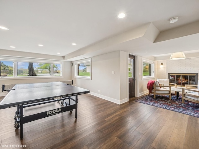recreation room featuring a fireplace, radiator, recessed lighting, baseboards, and wood finished floors