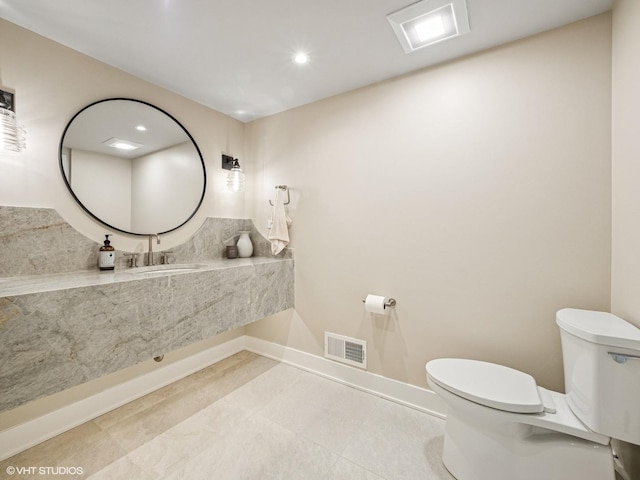 half bath with visible vents, toilet, baseboards, recessed lighting, and a sink
