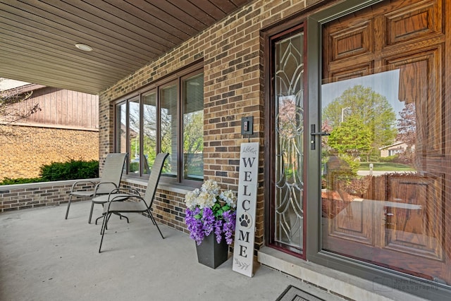 view of exterior entry with covered porch and brick siding