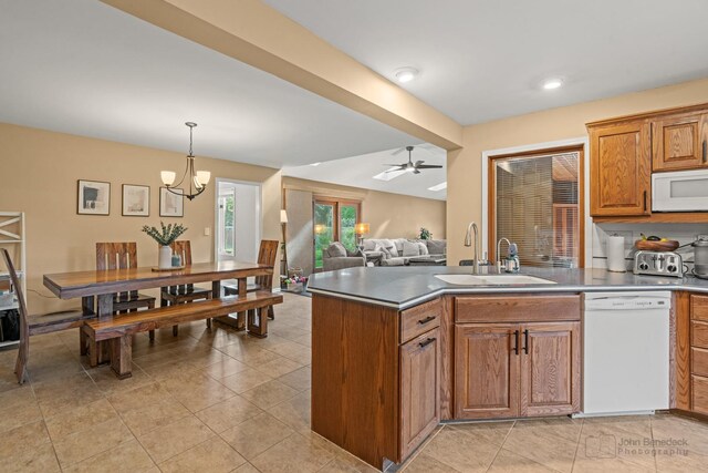 kitchen with white appliances, a sink, a ceiling fan, brown cabinets, and hanging light fixtures
