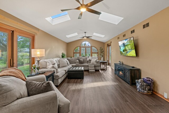 living area featuring a skylight, ceiling fan, dark wood-type flooring, and lofted ceiling