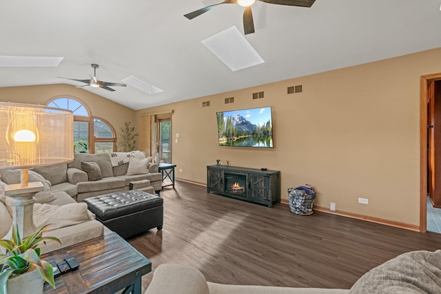 living room featuring a ceiling fan, a skylight, vaulted ceiling, wood finished floors, and baseboards