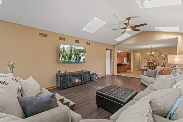 living area with a skylight, a chandelier, wood finished floors, a ceiling fan, and a glass covered fireplace