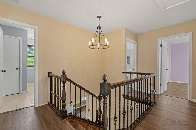 stairs with wood finished floors, a chandelier, and baseboards