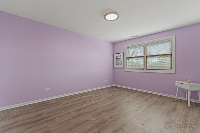 spare room featuring wood finished floors and baseboards