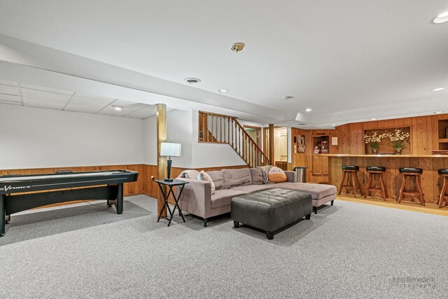 carpeted living room with a dry bar, stairway, a wainscoted wall, wood walls, and recessed lighting