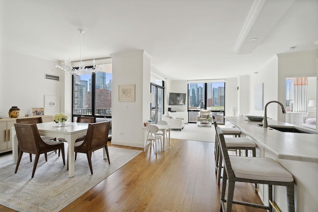 dining area with light wood-style floors, ornamental molding, a notable chandelier, and visible vents