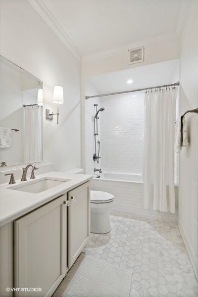 bathroom featuring vanity, ornamental molding, toilet, and tiled shower / bath combo
