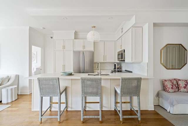 kitchen with a breakfast bar area, a peninsula, appliances with stainless steel finishes, and a sink