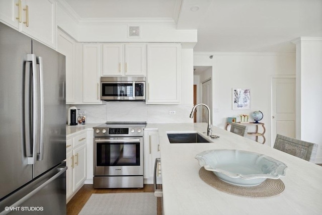 kitchen featuring crown molding, white cabinets, a sink, stainless steel appliances, and visible vents